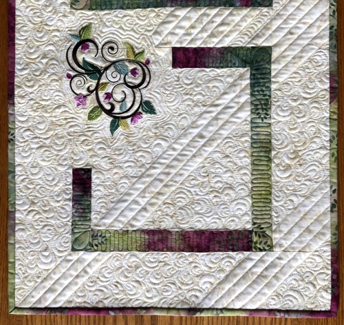 Quilted tablerunner with floral machine embroidery.Close-up of the lower part.