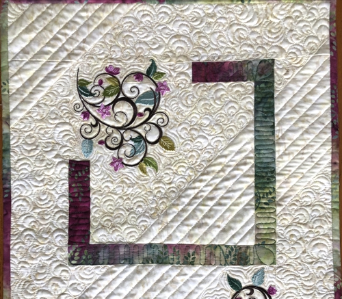 Quilted tablerunner with floral machine embroidery. Clcose-up of the upper part.