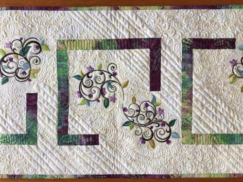 Quilted tablerunner with floral machine embroidery.