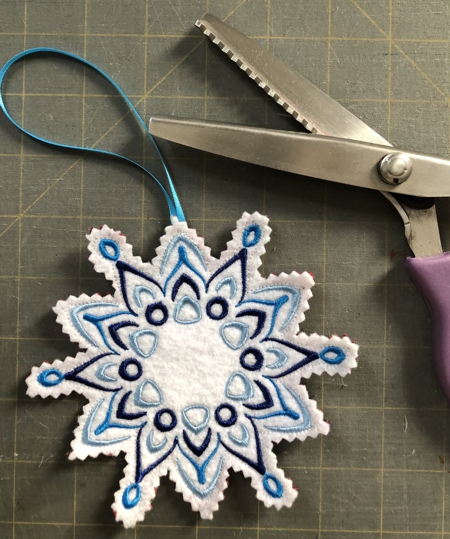 A finished snowflake ornament with a pair of shears.