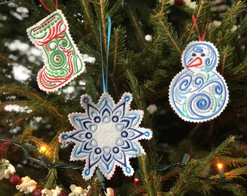 Finished ornaments of a stocking, snowman and a snowflake on a Christmas tree.