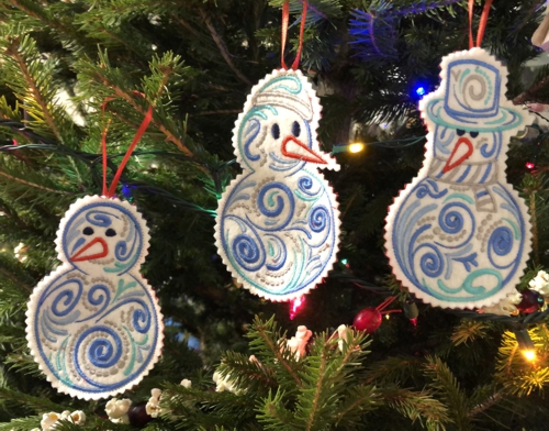3 snowmen ornaments on a Christmas tree.