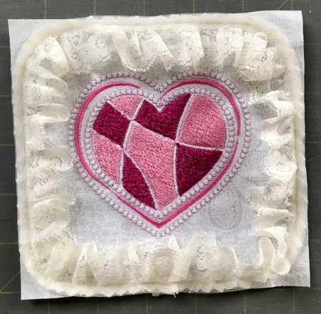 Embroidered square with attached lace.