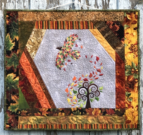 FInished wall quilt in fall colors and with fall tree and raven embroidery