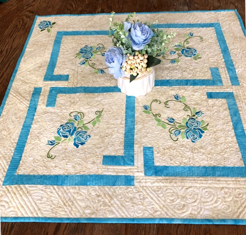 Finished tabletopper with blue roses embroidery.