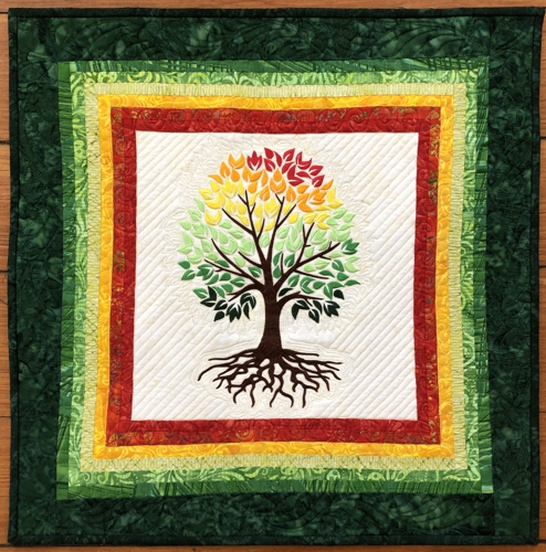 Finished quilted wallhanging with embroidery of a tree with multi-colored foliage