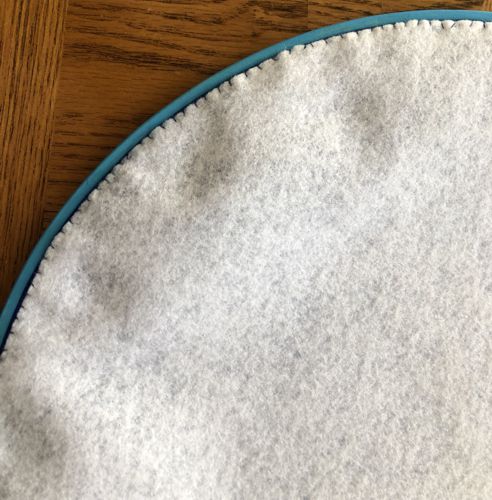 Cover the back with the felt circle and stitch it to the fabric along the edges