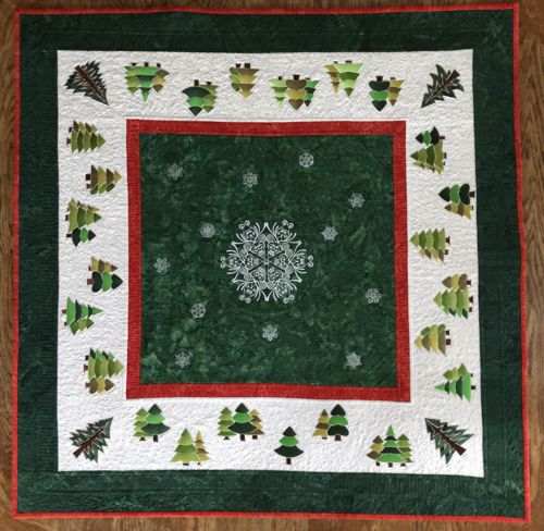 Finished quilted table topper with snowflake and pine tree embroidery