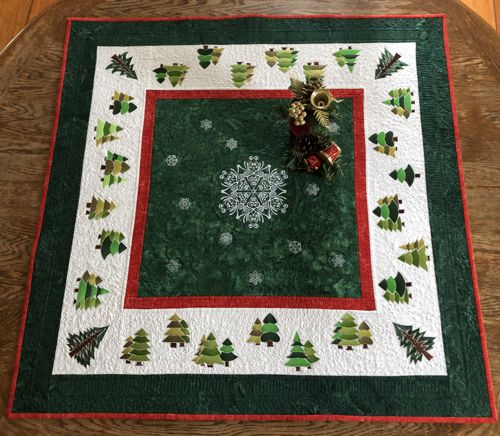 Finished quilted table topper with snowflake and pine tree embroidery