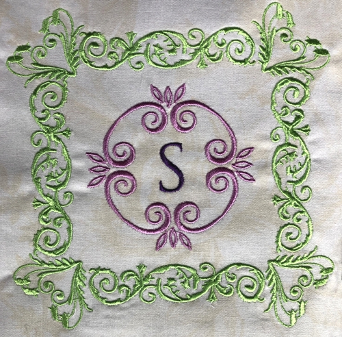 Embroidery of a letter S in a frame.