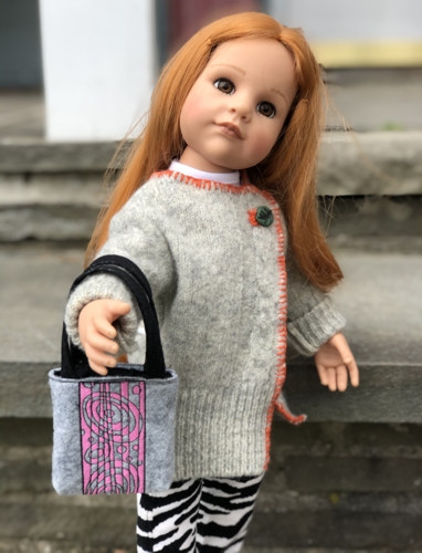 A doll carrying the gray bag.