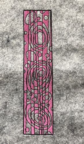 Stitch-out of a bookmark on gray felt.