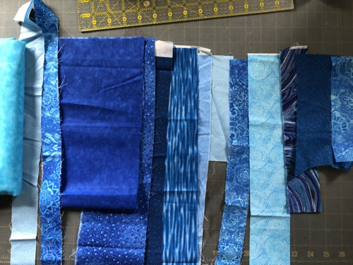 Scraps of blue fabrics arranged on a table in order they are used.