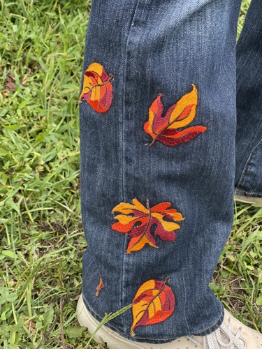 Jeans embellished with leaves embroidery. Close-up