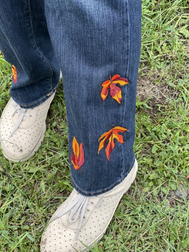 Jeans embellished with leaves embroidery. Close-up