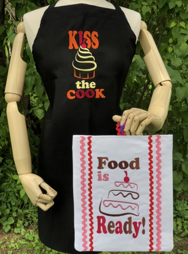 Black apron with "Kiss a cook" embroidery and a kitchen sign with "food is ready" embroidery