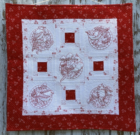 Finished red-and-white wall quilt with one-color bird embroidery