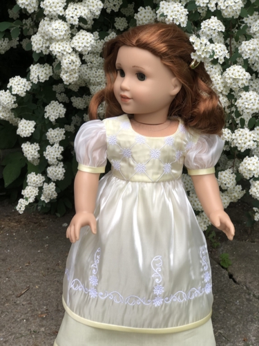 A doll in yellow dress with embroidered short organza overlay.