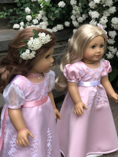 2 dolls in pink dresses with embroidery.