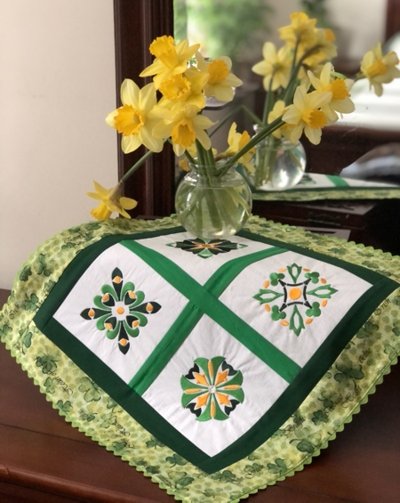 Finished doily with 4 embroidered squares and green borders.