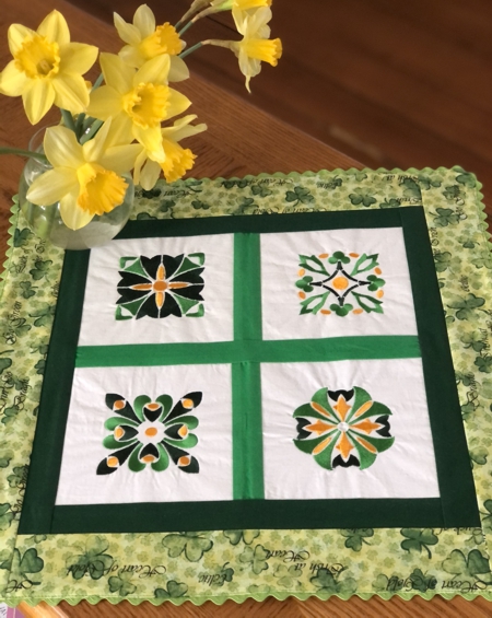 Finished doily with 4 embroidered squares and green borders.