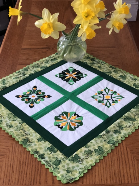 Finished doily with 4 embroidered squares and green borders.