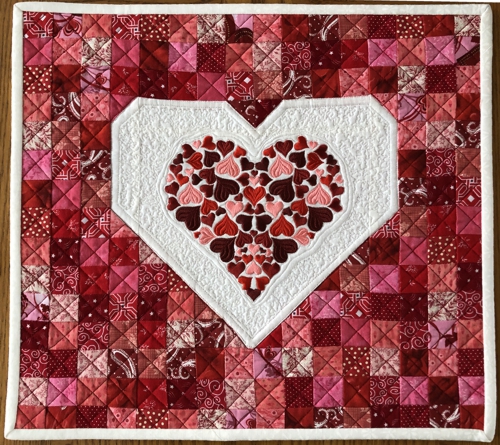 FInished Valentine wall quilt with embroidery in the center.