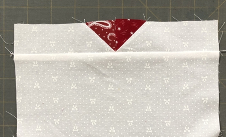 Sew the strip to the upper edge of the white square.