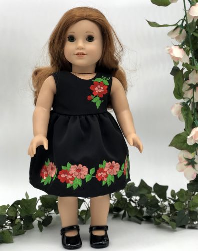 A doll in the finished black dress with embroidery.