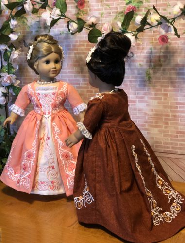 Photo of two 18-inch dolls modelling the formal colonial dress decorated with the machine embroidery