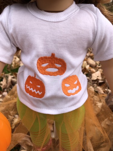 A close-up of a doll t-shirt with Jack-o-Lantens.