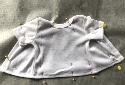 A doll t-shirt pinned to a sheet of stabilizer.