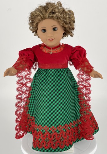 The finished dress and shawl on a doll.