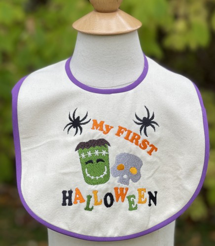A bib with Halloween-themed embroidery and bias tape finished edges.