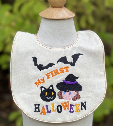 The bib with Halloween-themed embroidery and topstitched edges.