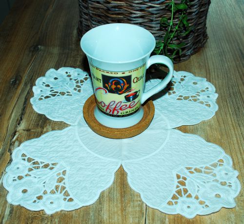 The stitch-out of the doily on a table with a mug.