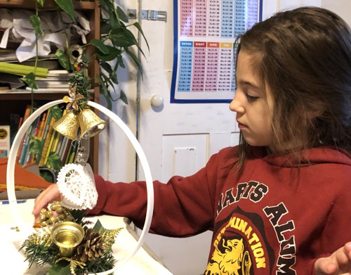 A girl with a white hoop, green branch glued to the stand, white and blue angel stitch-outs.