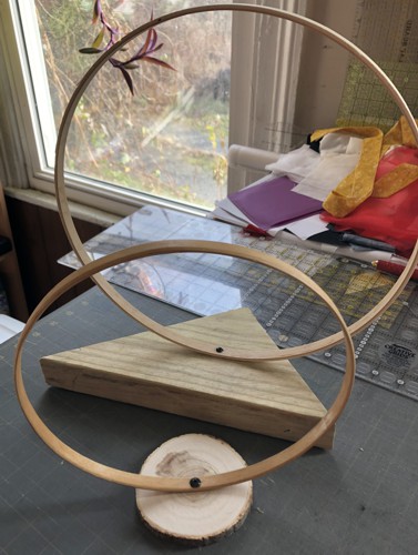 Embroidery hoops attached to the pieces of wood with a screw.