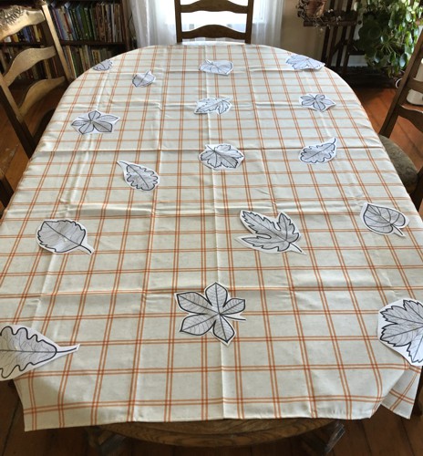 Paper print-outs of the designs arranged on the tablecloth.