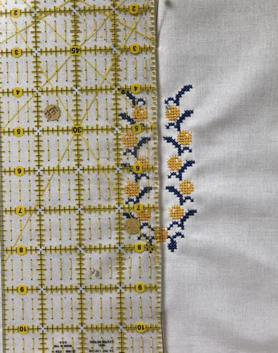 Position the rular along the central vertical line of the embroidery.