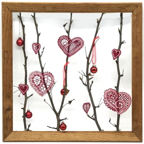 Finished project of the picture frame with twigs and red heart stitch-outs.