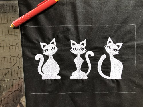 The finished embroidery - grey cats on black background.