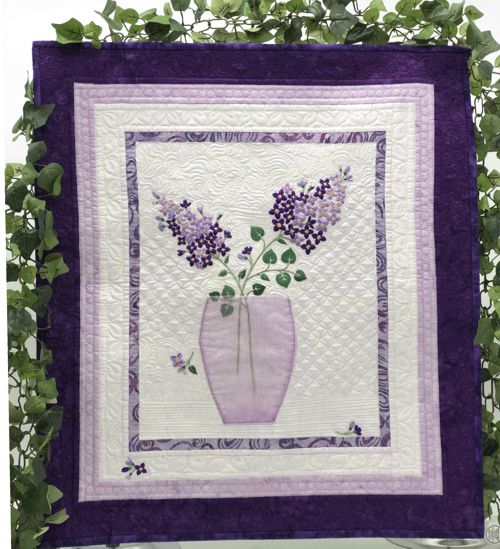 Finished art quilt with lilac embroidery and applique vase.