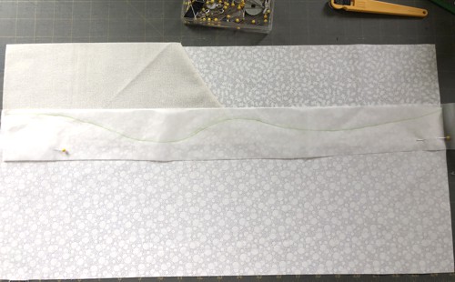 A strip of parchment with a curved line over the fabric.
