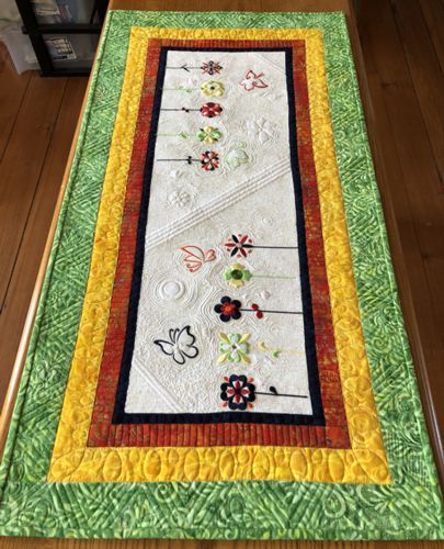 Quilted tablerunner with flower embroidery.