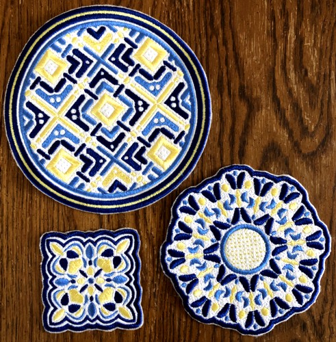 3 coasters embroidered in blue and yellow threads.