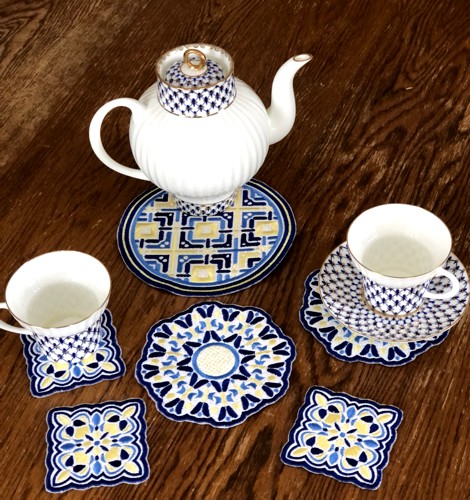 Party coasters with a teapot, tea cups and plates on a table .