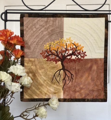 the quilt with Autumn tree in light beige, golden, and brown hues.