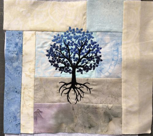 A stitch-out of the blue tree on the gray-blue background.