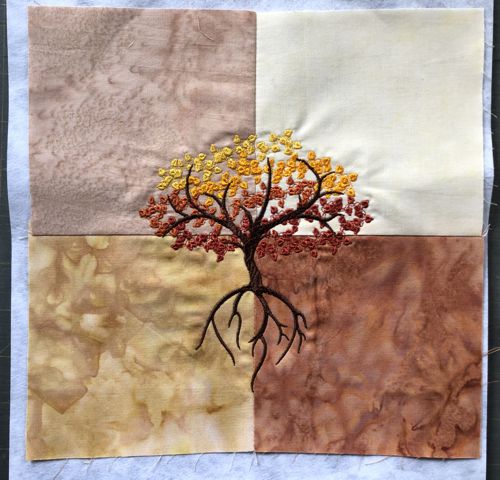 Stitch-out of the fall tree on the beige-brown background.